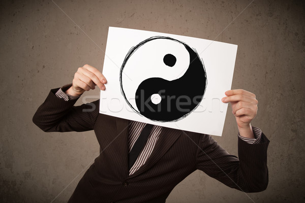 Businessman holding a paper with a yin-yang on it in front of hi Stock photo © ra2studio