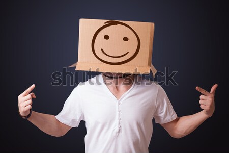 Stock photo: Young man gesturing with a cardboard box on his head with smiley