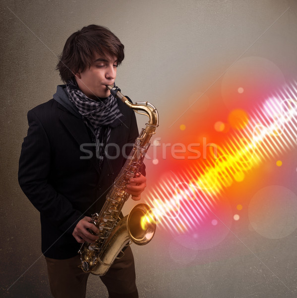 Young man playing on saxophone with colorful sound waves Stock photo © ra2studio