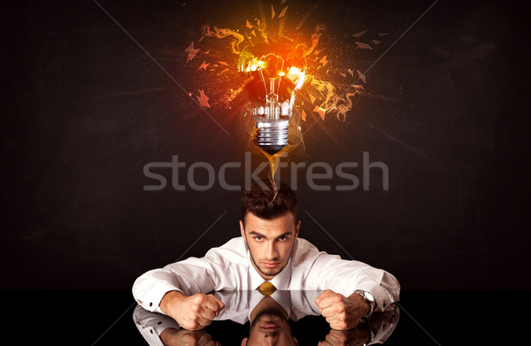 Businessman sitting under a blowing idea bulb Stock photo © ra2studio