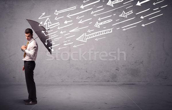 Business man standing with umbrella and drawn arrows hitting him Stock photo © ra2studio