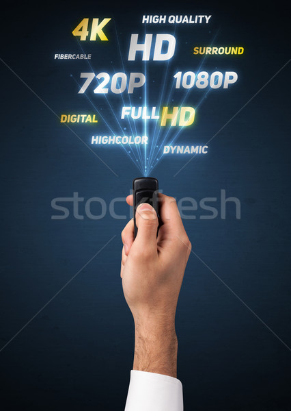 Stock photo: Hand with remote control and multimedia properties