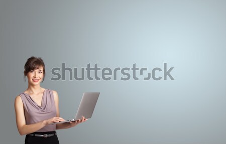 attractive woman holding a laptop with copy space Stock photo © ra2studio