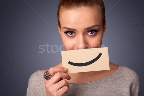 Happy pretty woman holding card with funny smiley Stock photo © ra2studio