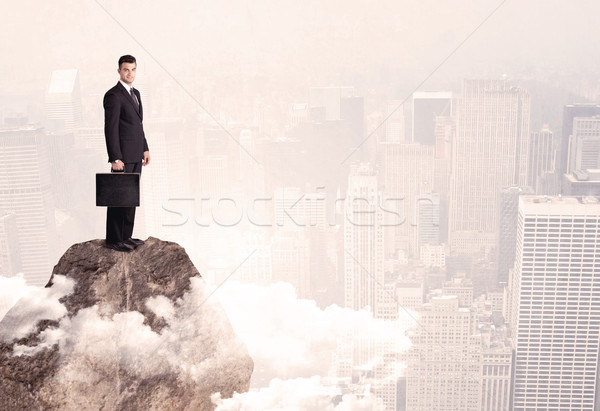 Happy businessman standing on stone top Stock photo © ra2studio