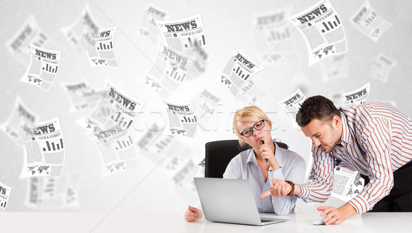 Business man and woman at desk with stock market newspapers Stock photo © ra2studio