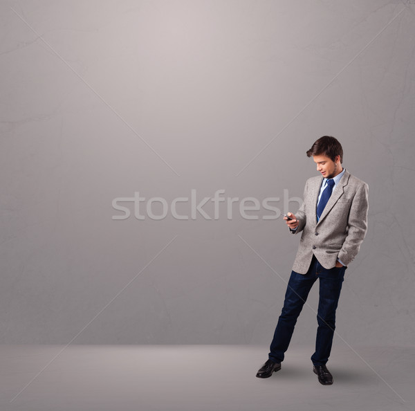 handsome boy standing and holding a phone Stock photo © ra2studio