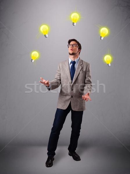 young man standing and juggling with light bulbs Stock photo © ra2studio