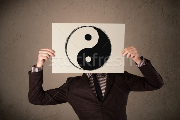Businessman holding a paper with a yin-yang on it in front of hi Stock photo © ra2studio