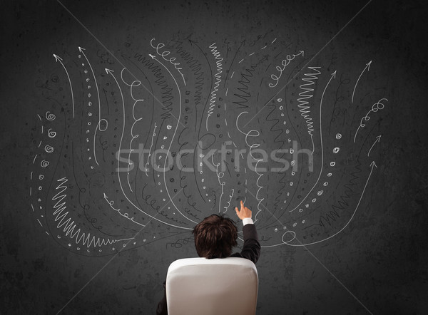 Stock photo: Businessman thinking with sketched arrows in front of a chalkboa