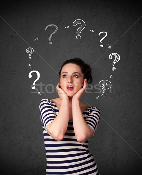 Stock photo: Young woman thinking with question mark circulation around her h