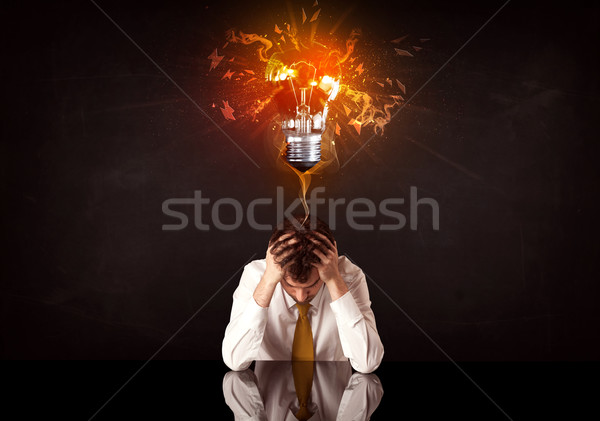 Businessman sitting under a blowing idea bulb Stock photo © ra2studio