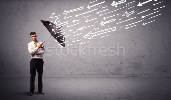 Business man standing with umbrella and drawn arrows hitting him Stock photo © ra2studio