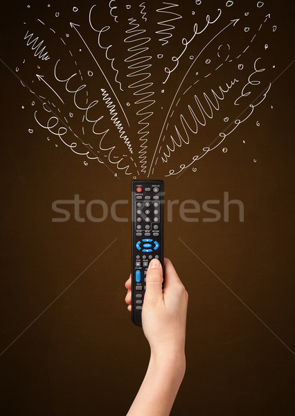 Hand with remote control and curly lines Stock photo © ra2studio