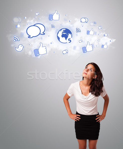 Stock photo: pretty woman looking social network icons in abstract cloud