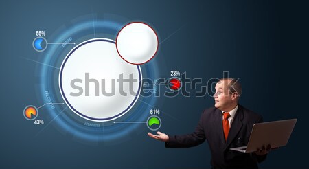 Stock photo: businessman in suit holding a laptop and presenting abstract modern pie chart