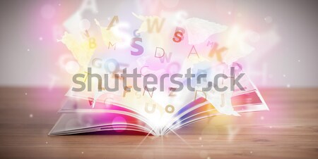 Open book with glowing letters on concrete background Stock photo © ra2studio