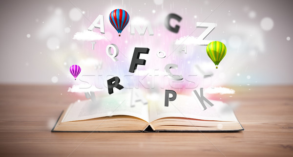 Open book with flying 3d letters on concrete background Stock photo © ra2studio