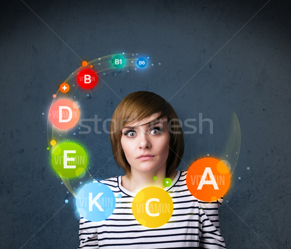 Young woman thinking with vitamins circulation around her head Stock photo © ra2studio