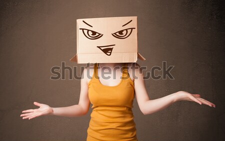 Young man gesturing with a cardboard box on his head with evil f Stock photo © ra2studio