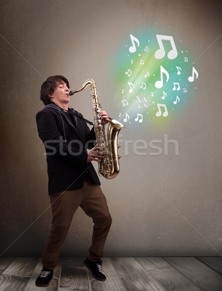 Jovem músico jogar saxofone notas musicais atraente Foto stock © ra2studio