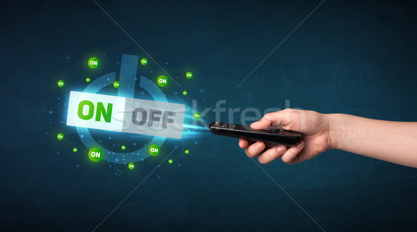 Stock photo: Hand with remote control and on-off signals
