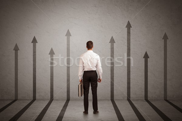 Sales person looking at arrows pointing up on the wall concept Stock photo © ra2studio