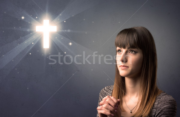 Jonge vrouw bidden grijs kruis boven Stockfoto © ra2studio