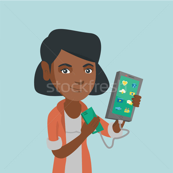 Woman reharging smartphone from portable battery. Stock photo © RAStudio