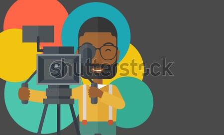African cameraman with movie camera on tripod. Stock photo © RAStudio
