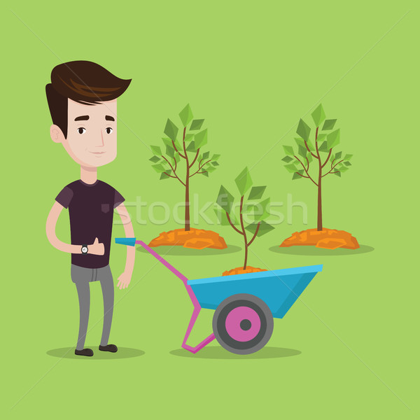 Stock photo: Man pushing wheelbarrow with plant.