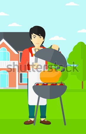 Stock photo: Man cooking chicken on barbecue grill.