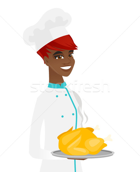 Young african chef holding roasted chicken. Stock photo © RAStudio