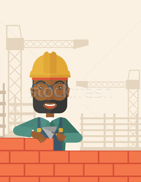 Black builder man is building a brick wall. Stock photo © RAStudio