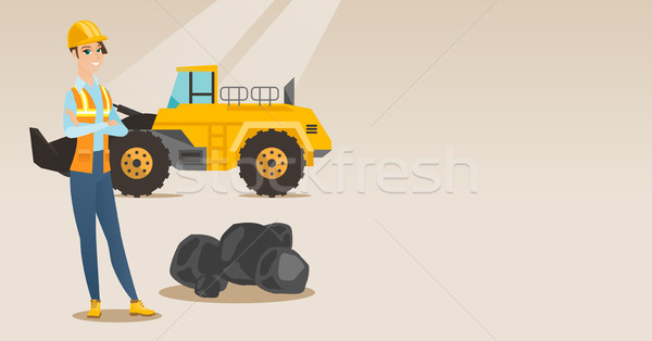 Stock photo: Miner with a big excavator on background.