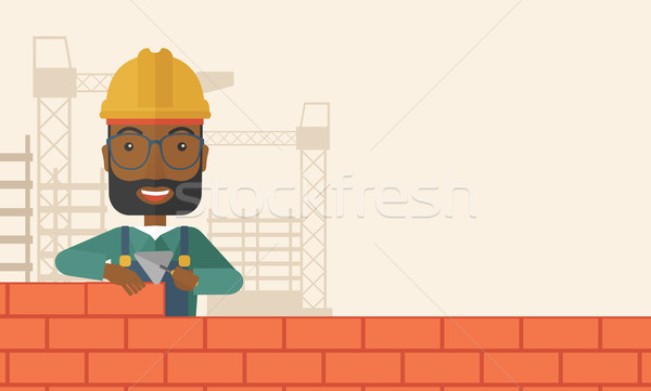Black builder man is building a brick wall. Stock photo © RAStudio