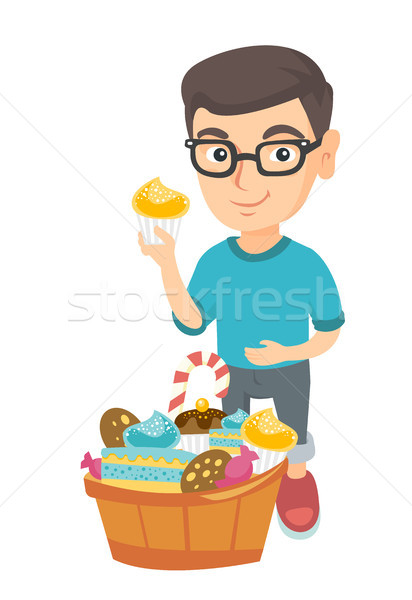 Boy holding a cupcake and stroking his belly. Stock photo © RAStudio