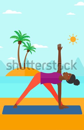 Woman practicing yoga triangle pose on the beach. Stock photo © RAStudio