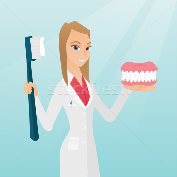 Dentist with a dental jaw model and a toothbrush. Stock photo © RAStudio