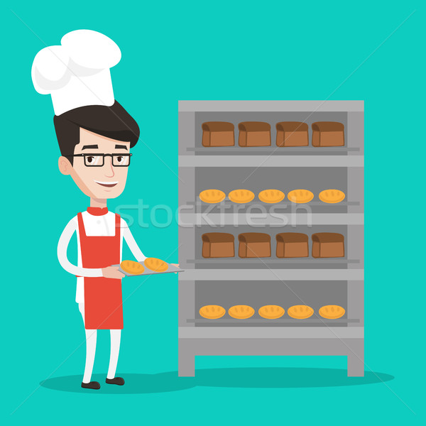 Happy young male baker holding tray of bread. Stock photo © RAStudio