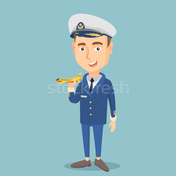 Stock photo: Cheerful airline pilot with model of airplane.