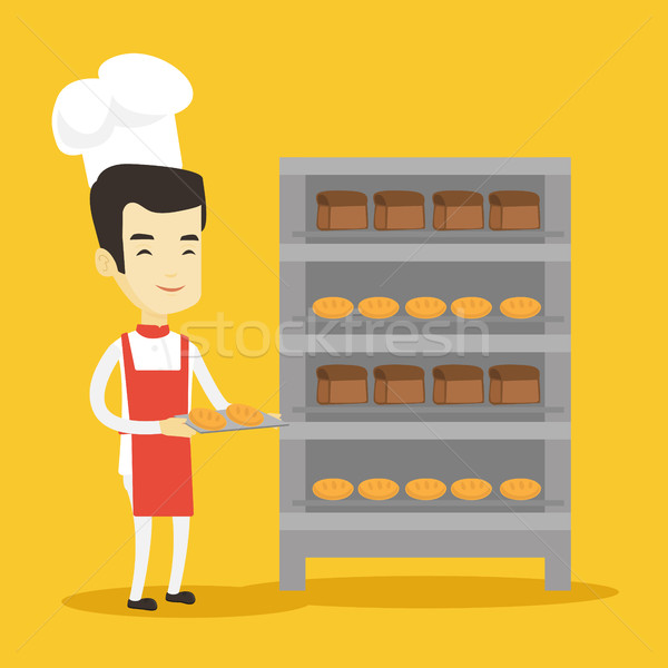 Happy young male baker holding tray of bread. Stock photo © RAStudio