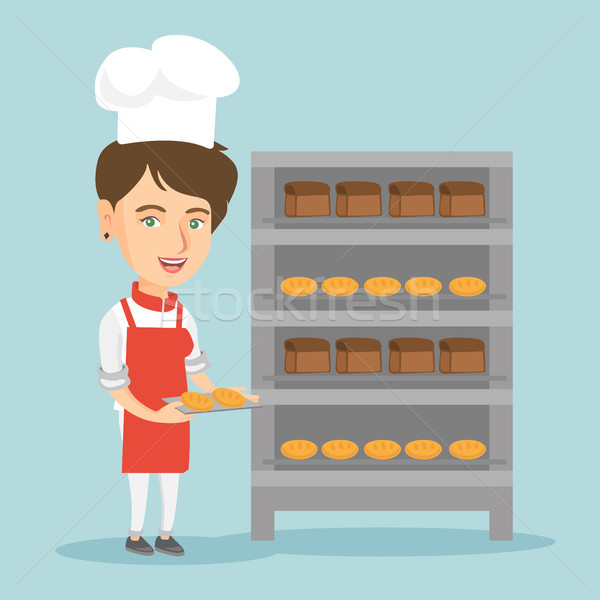 Young caucasian baker holding a tray with bread. Stock photo © RAStudio