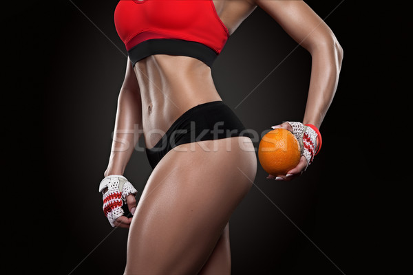 Beautiful sportly fitness girl holding an orange Stock photo © restyler
