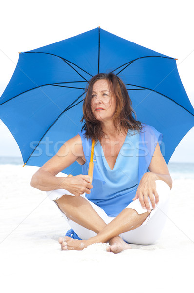 Worried Mature woman blue umbrella beach Stock photo © roboriginal