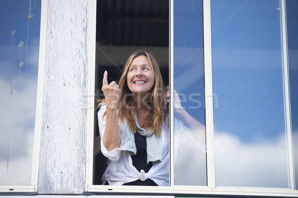 Cheeky happy woman at window finger signal Stock photo © roboriginal