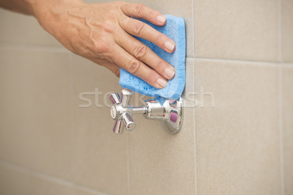 Cleaning water tap in bath with sponge Stock photo © roboriginal