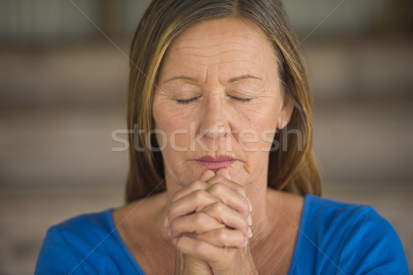 Woman praying closed eyes folded hands Stock photo © roboriginal