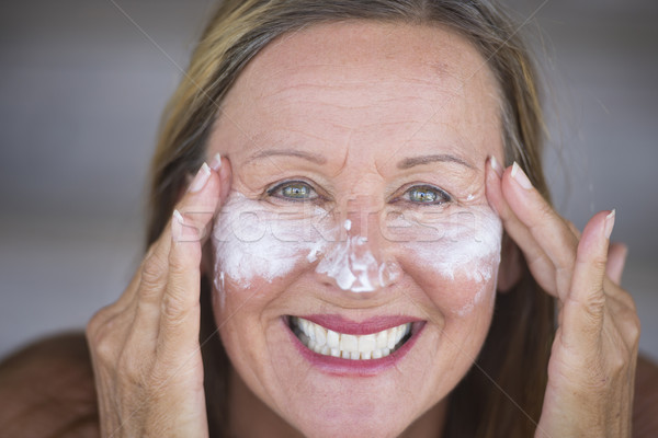 Joyful mature woman face creme skin care Stock photo © roboriginal