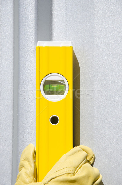 Stock photo: Hands with gloves on spirit level metal background